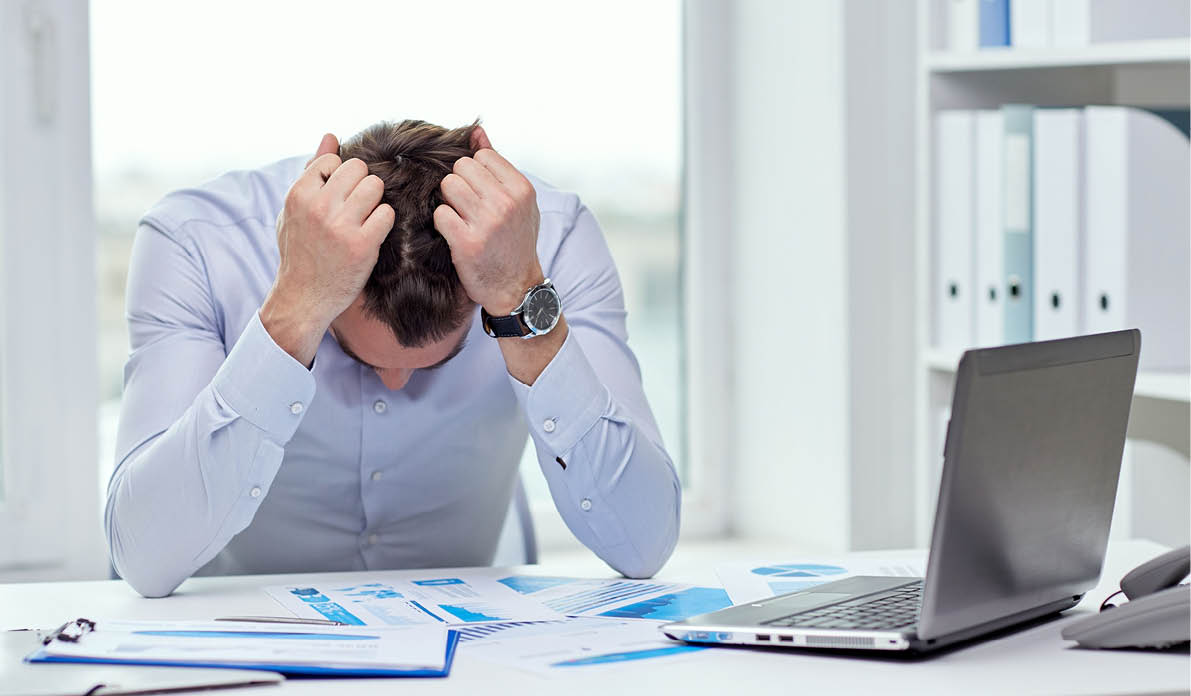 business, people, paperwork and deadline concept - stressed businessman with papers and charts sitting at table in office