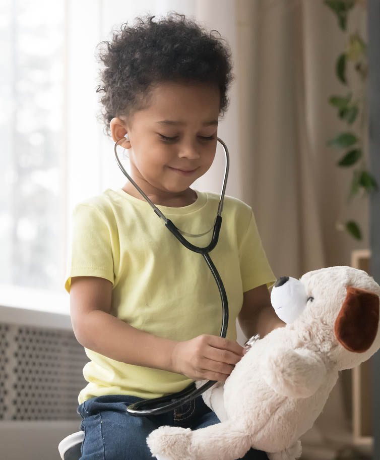 Cute little toddler african american boy playing funny game as doctor holding stethoscope listening to toy, mixed race black preschool child kid pretending nurse treating fluffy patient at home