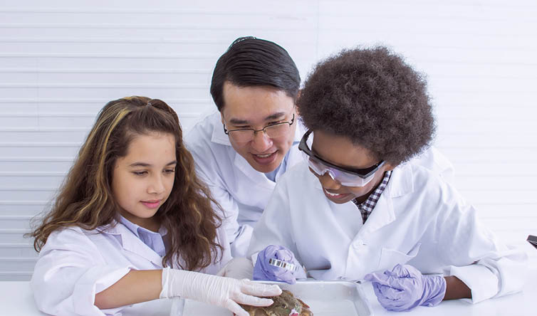 Asian male teacher is teaching biology to caucasian and african students in laboratory at school  Education, Diversity and Sciences Concept 