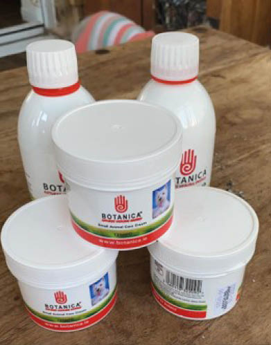 Several white containers of Botanica brand animal care products are arranged on a wooden surface. Description generated by AI