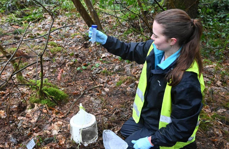 A woman wearing a yellow vest is holding a blue bottle and a blue cup. AI generated content