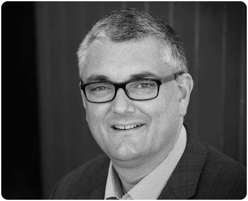 A man wearing glasses and a suit is smiling for the camera. AI generated content