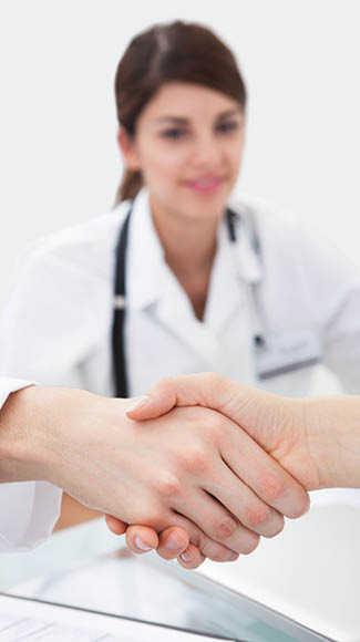 Cropped image of doctors shaking hands at desk in clinic
