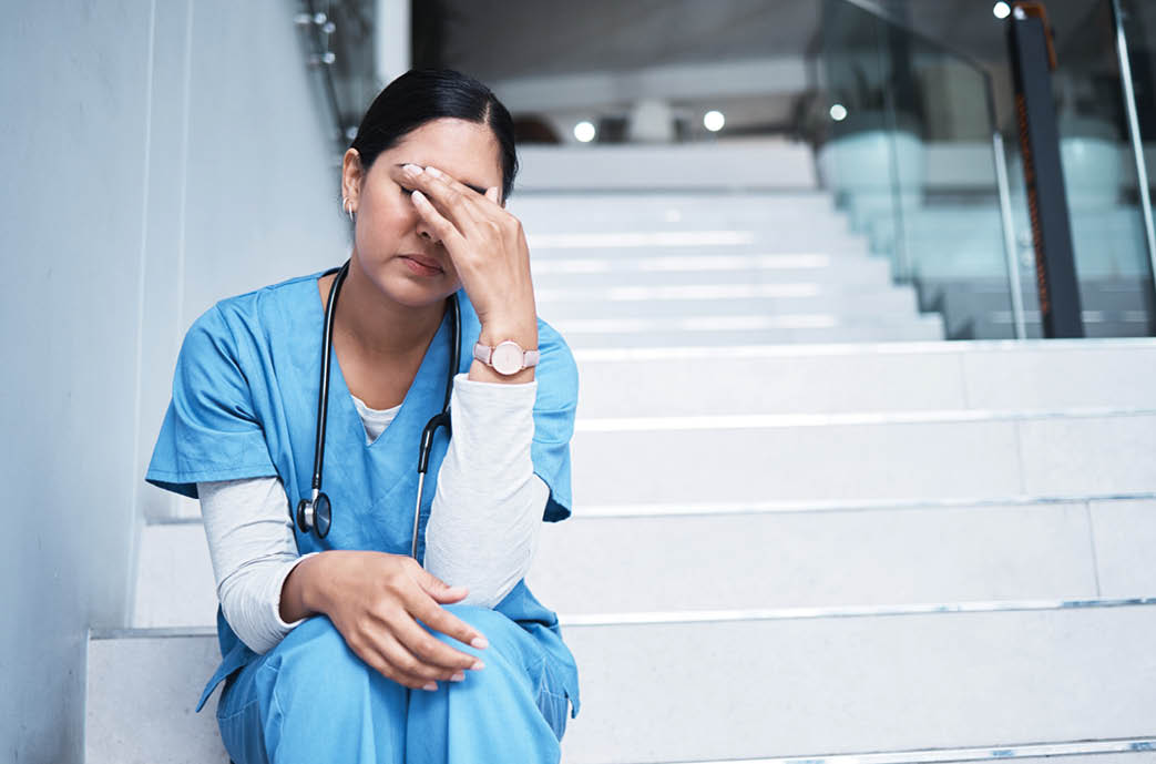 Sometimes not everything is in our hands. Shot of a female nurse looking stressed while sitting on a staircase.
