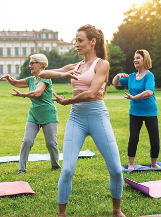 Multiethnic group of senior women training at park with fitness instructor - Active elderly people doing sport in the nature