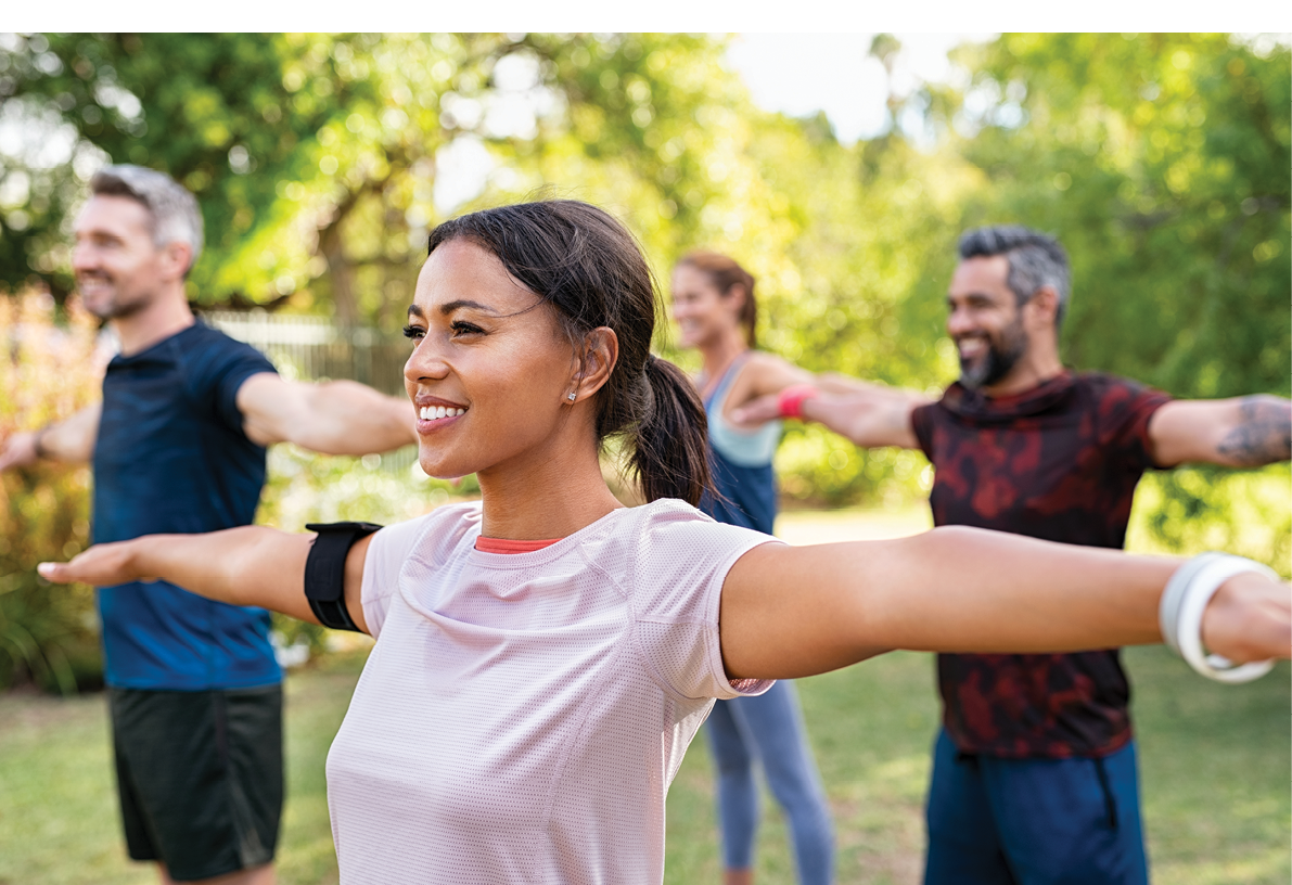 Group of multiethnic mature people stretching arms outdoor. Middle aged yoga class doing breathing exercise at park. Beautifil women and fit men doing breath exercise together with outstretched arms.  