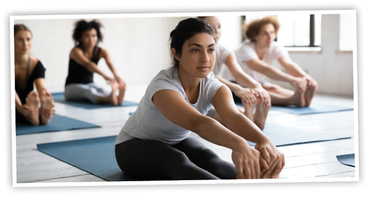Indian ethnicity instructor and diverse group of people sitting on mats performing Seated Forward Bend at morning work out activity, physical and mental health care, wellness healthy lifestyle concept