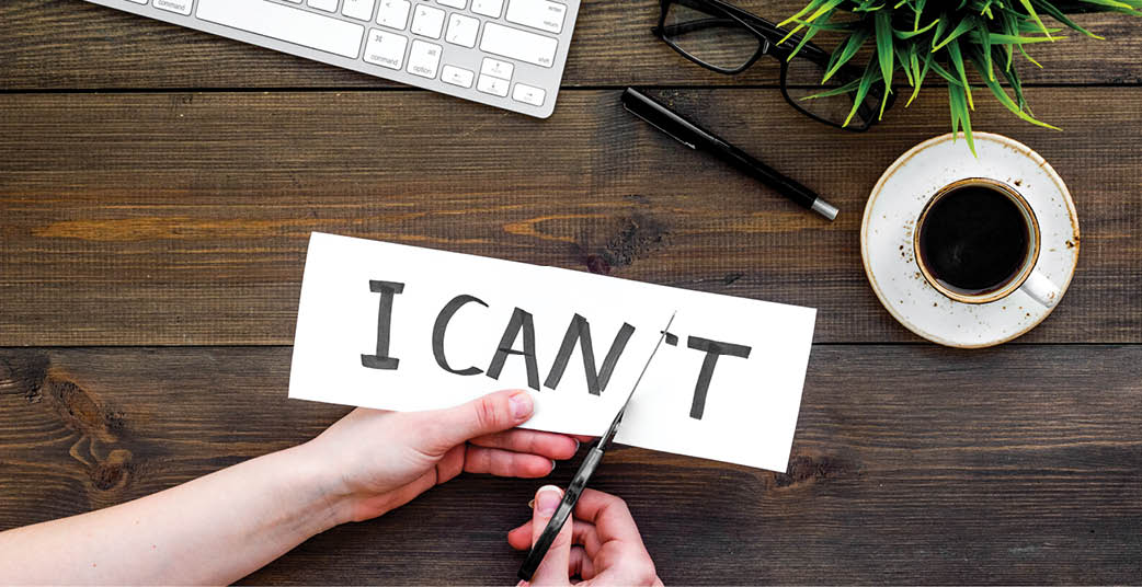 Self confidence concept. Hands cutting the letter t of written word I can't by sciccors. Office desk. Dark wooden background top view copy space